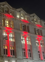 An image of 30 Euston Square lit up with red lights at night. 