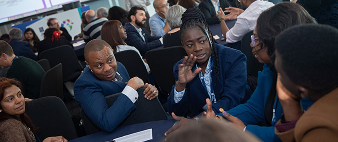 Delegates networking and sharing ideas at a conference, dressed in business attire. 