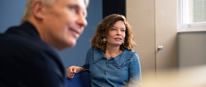 A woman with short hair and a man sitting parallel to her looking into the distance. 