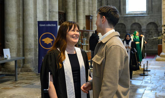 A man and woman smile while in conversation inside a large, stone church.