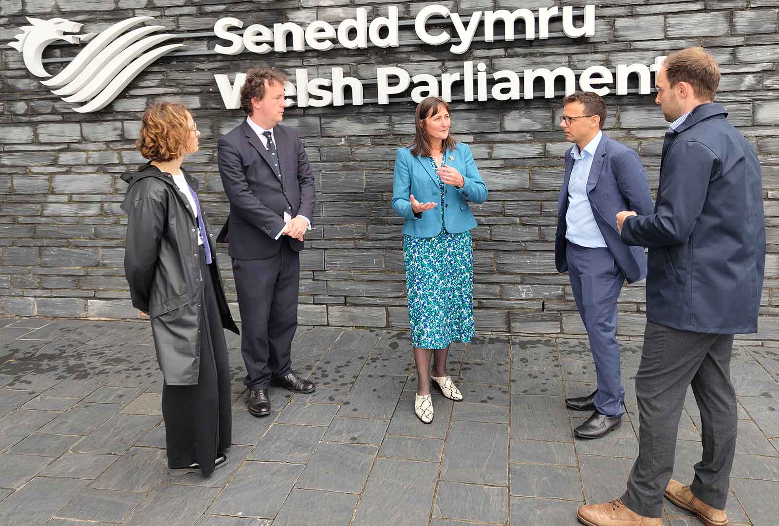 Image of Rowena Christmas-Senedd surrounded by 4 people, wearing blue coat outdoors