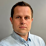 Square headshot of Dr Huw Miles, he is wearing a light blue shirt.