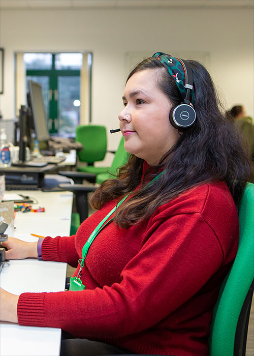 A worker at MacMillan at a desk wearing a headset.