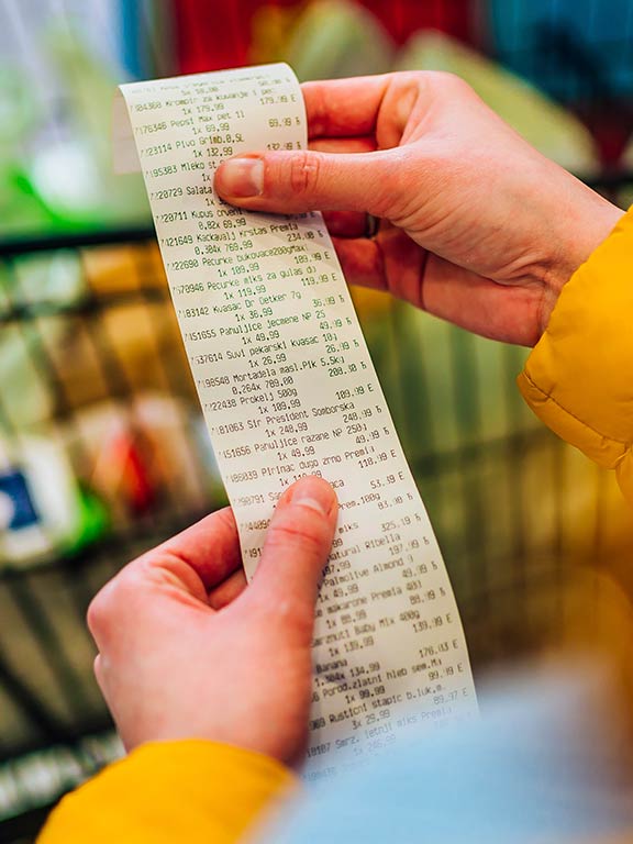 Hands holding a long receipt of bought items
