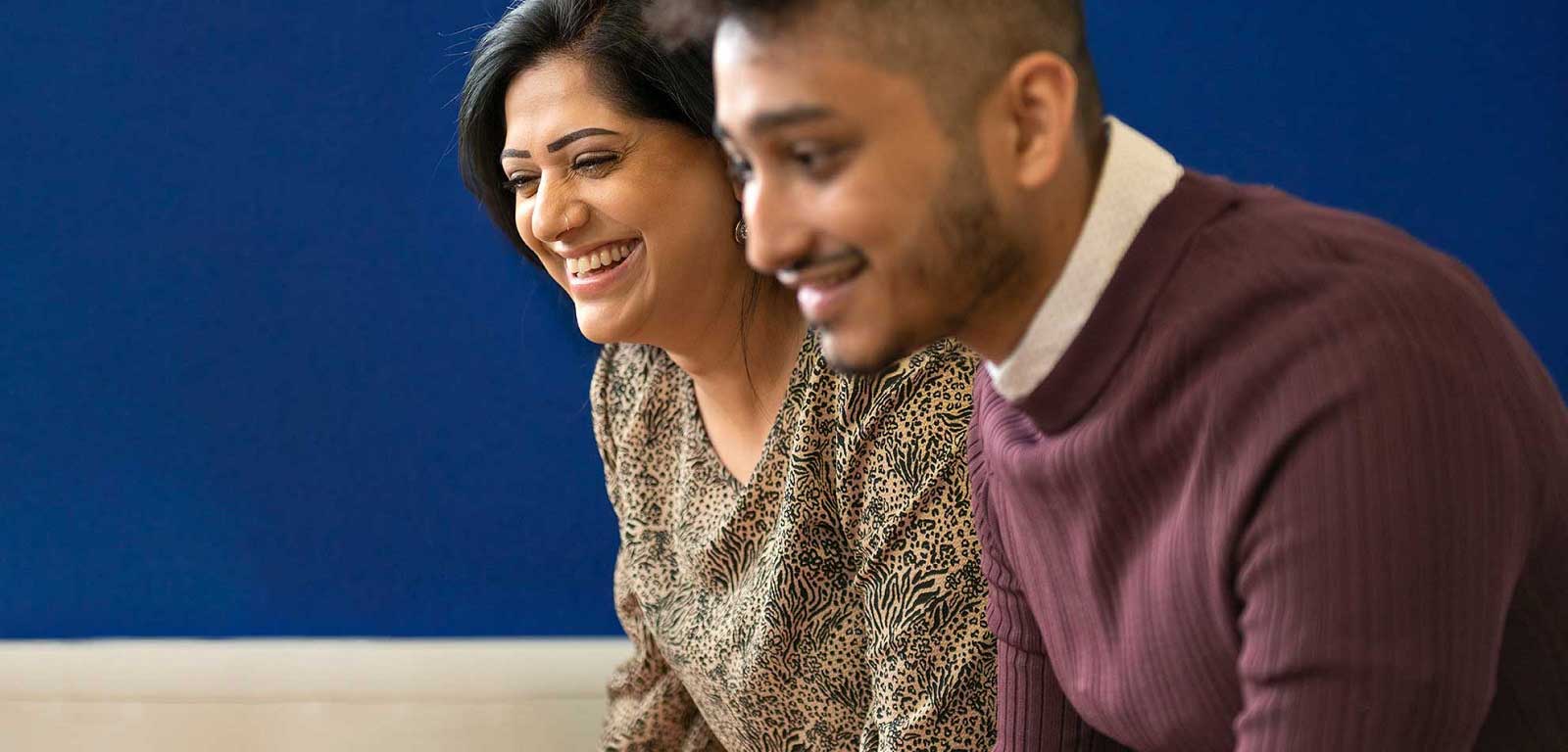 Two people, side-by-side, smiling down at something off-frame