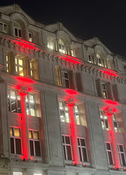 An image of 30 Euston Square lit up with red lights at night.