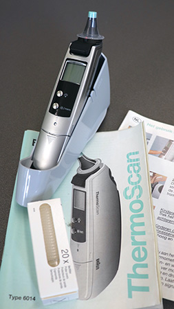 Braun's easy-to-use digital in-ear thermometer reads temperature sitting on the leaflet with instructions. There is a box of 20 disposable hygiene caps. Image from the RCGP collections.