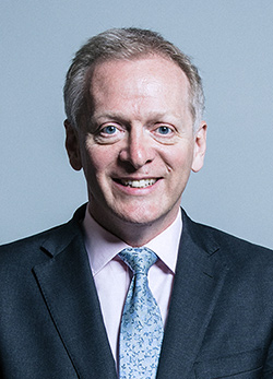 A head and shoulders image of Phillip Lee wearing a suit and light blue tie.