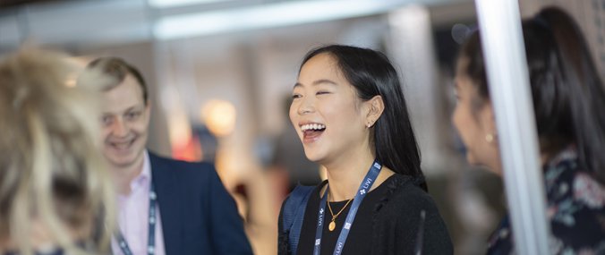 A laughing younger woman is in the center of a group at a large event.