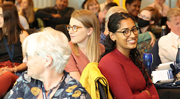 Women of a variety of ages sit at different tables at an event.