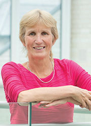 A small card image of Dr Anne Connolly wearing a bright pink top. 