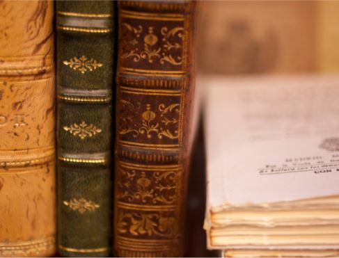A photograph of old book spines propped up by medical papers.