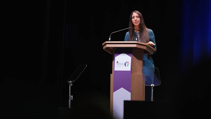 Woman on stage giving a talk at a pulpit