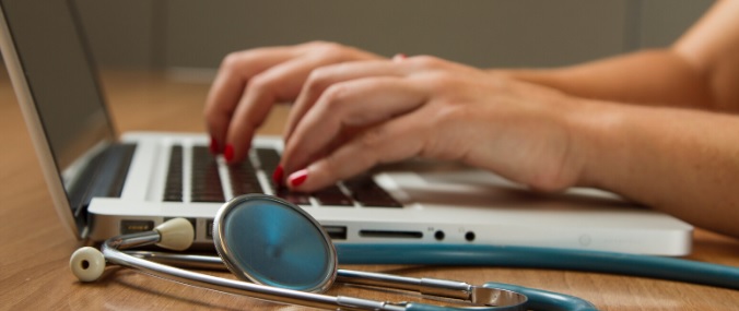 A pair of hands are typing on a silver laptop. 