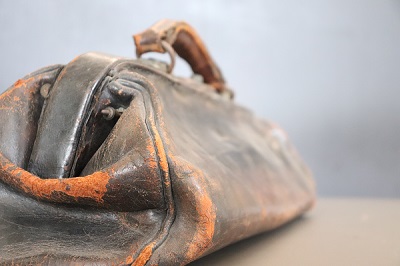 A close-up photo of a worn leather Gladstone bag from the late nineteenth century