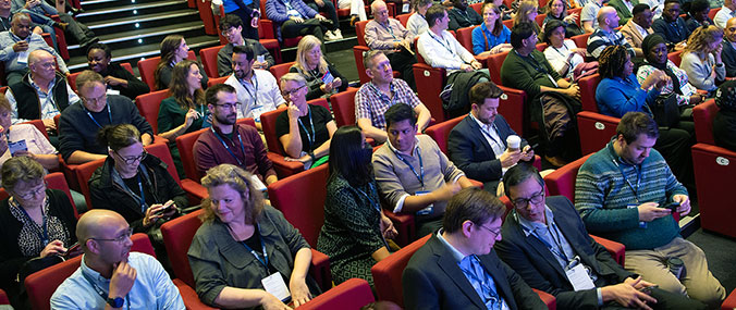 Large audience of conference delegates in packed auditorium
