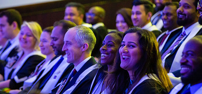 People sitting in a row, wearing gowns and smiling