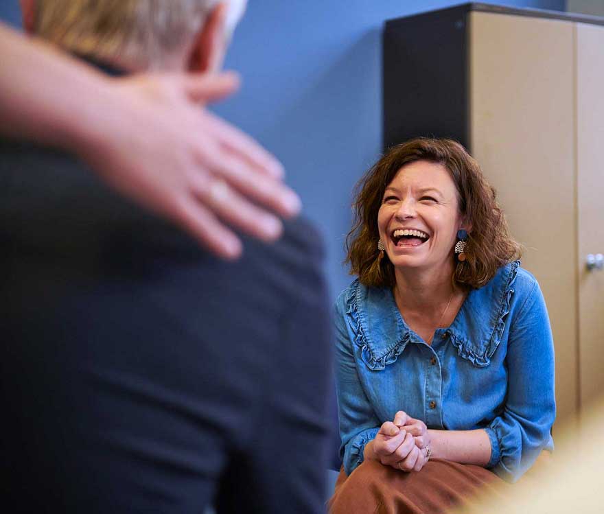 A woman laughing while speaking to some other people