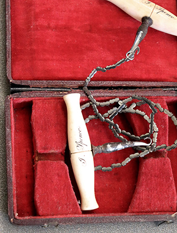 An ivory chainsaw is displayed in a red velvet case. The image is from the RCGP collections.