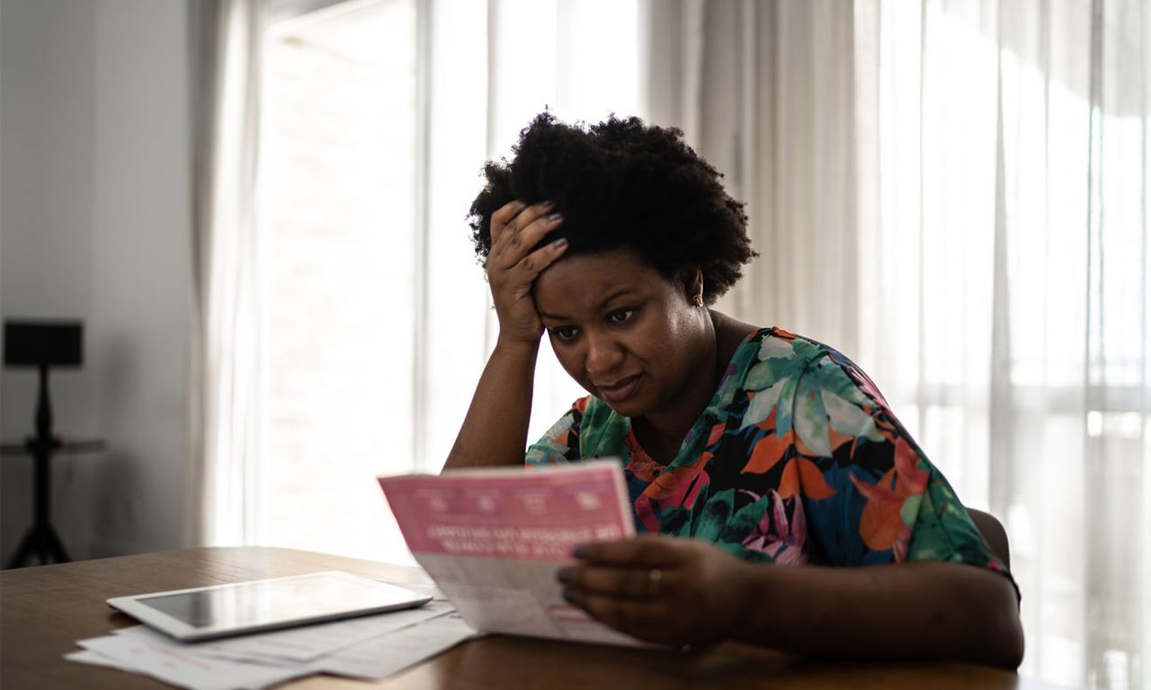 A woman looking at a bill and clutching her head