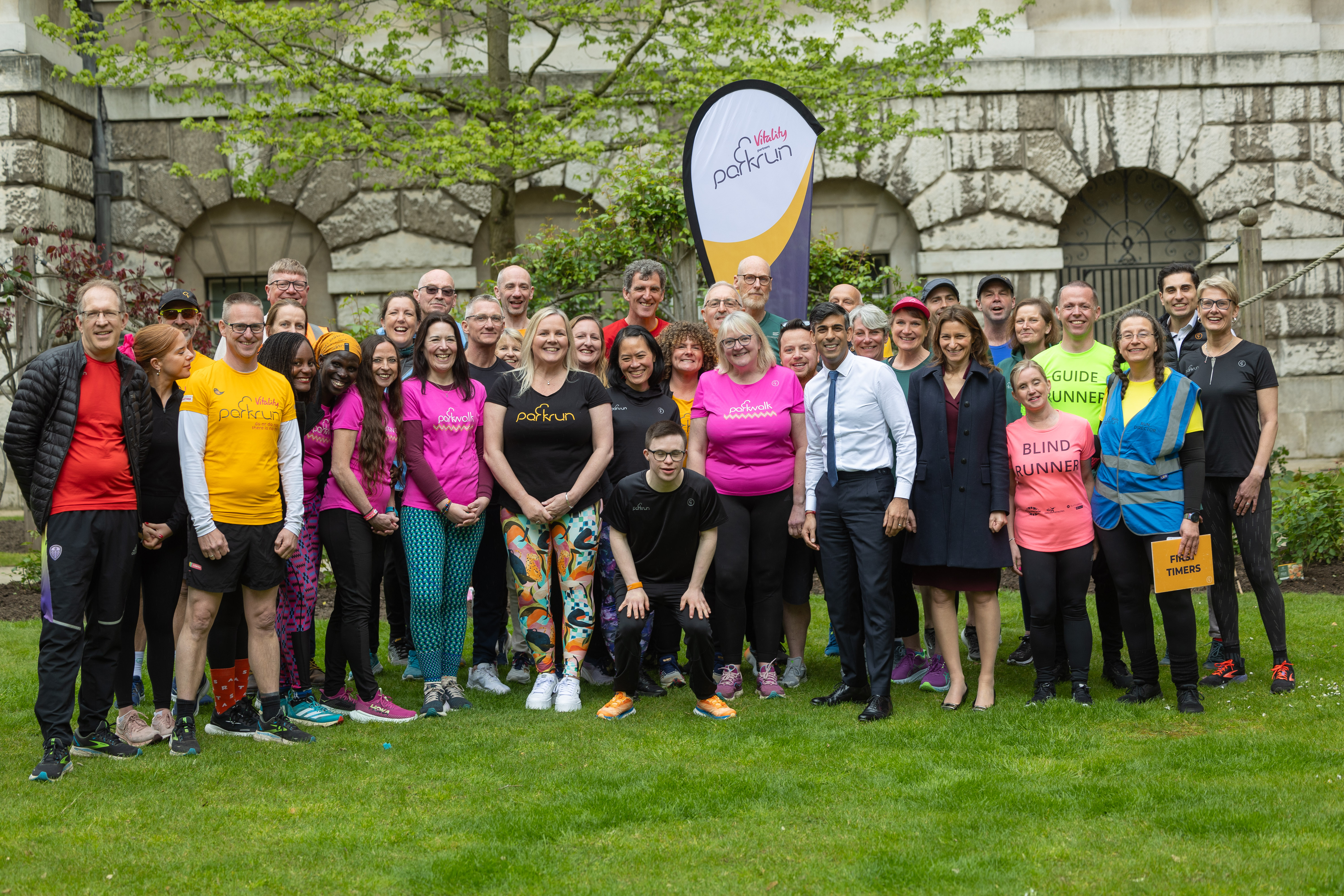 A group of parkrun representatives stand in the gardens of 10 Downing Street.  