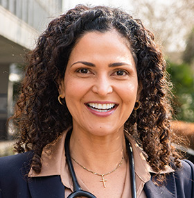 Dr Alba smiling whilst standing outside.