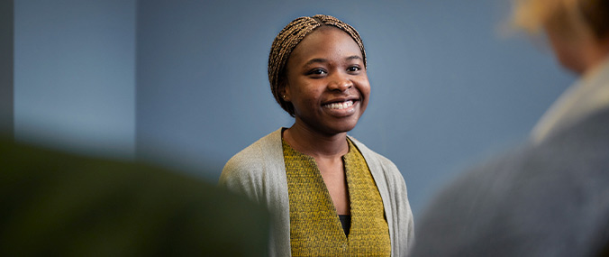 A woman smiling at two people standing in front of her. 