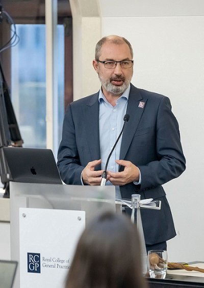 Dr Michael Mulholland standing at a podium in front of a crowd. 