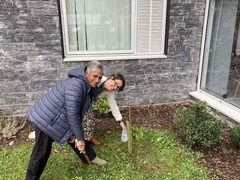 Kamila Hawthorne and a companion planting a tree in grass