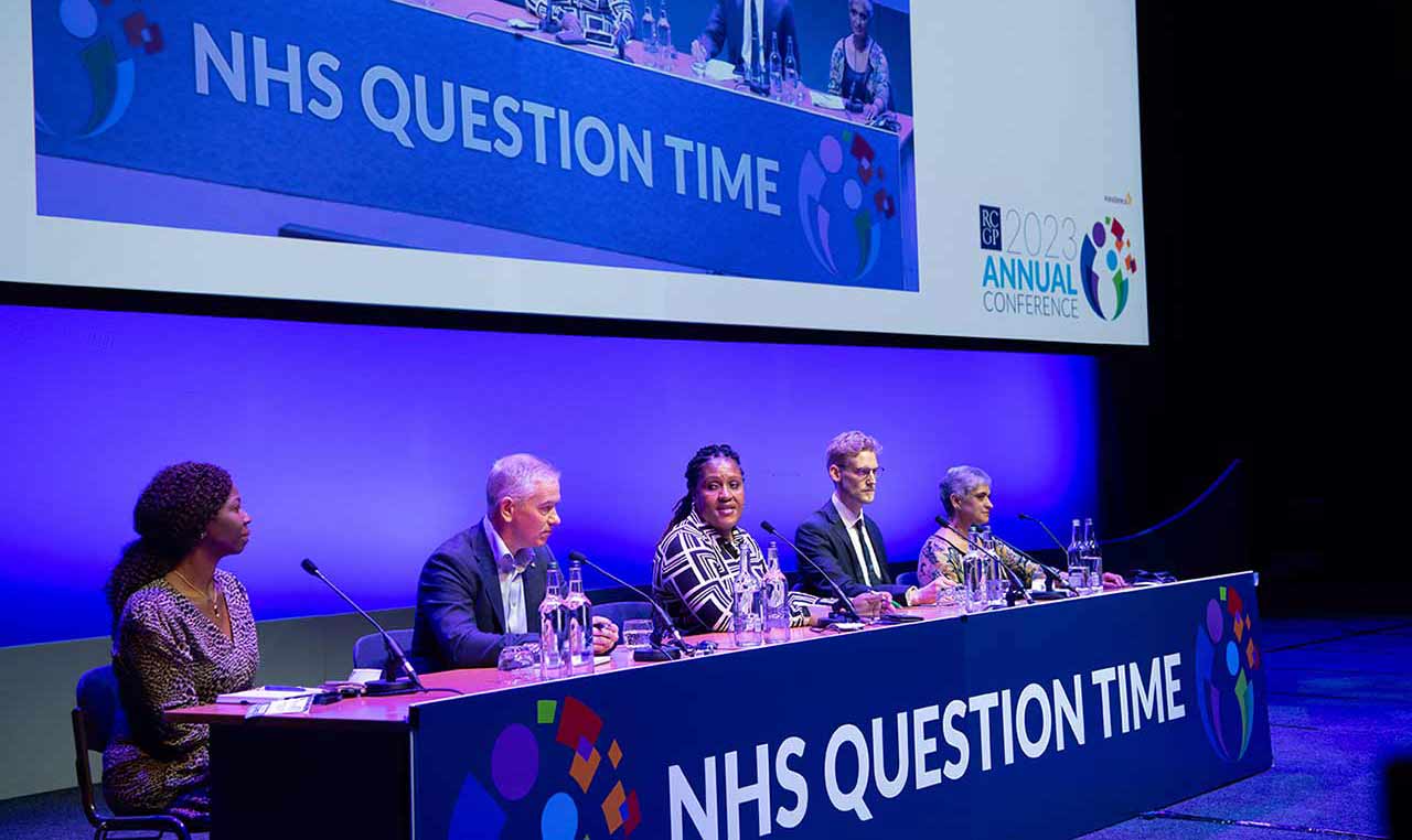 A panel sitting at a long table with a microphone for each speaker